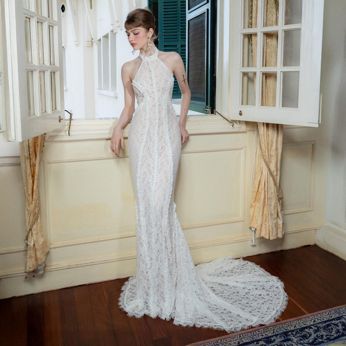 May include: A white lace halter-neck gown with a mermaid silhouette and a long train. The dress features intricate floral lace detailing and a high neckline. The gown is floor-length and appears to be made of delicate, flowing fabric.