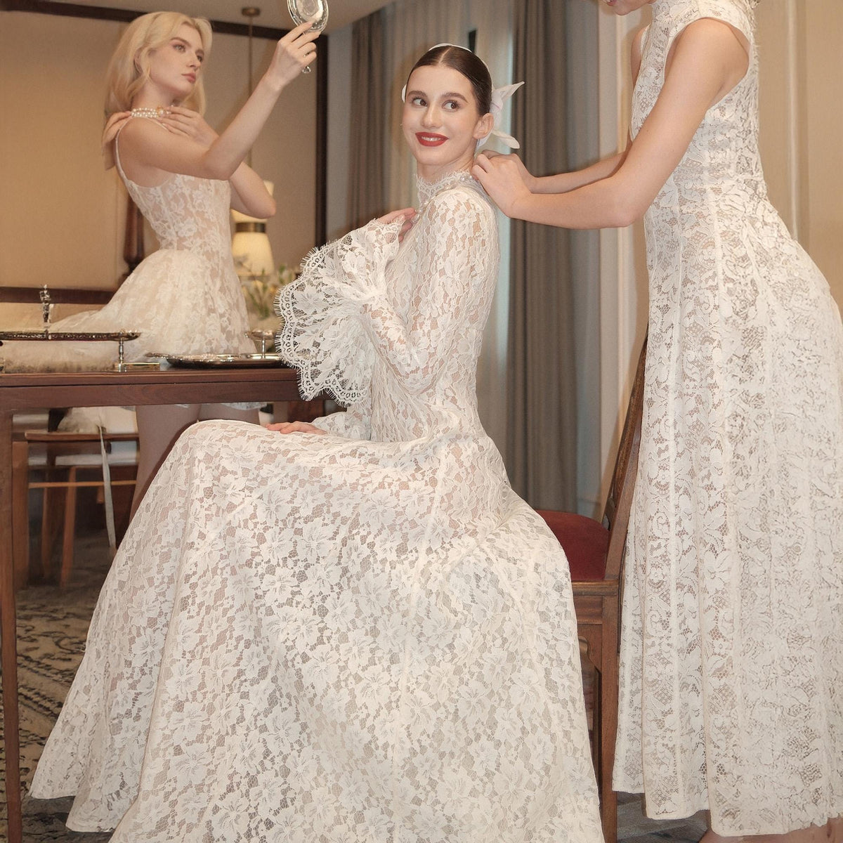 May include: A floor-length white lace dress featuring long sleeves with flared cuffs, a high neckline, and a fitted bodice that transitions into a full skirt. The intricate floral lace pattern covers the entire garment, creating a textured appearance.