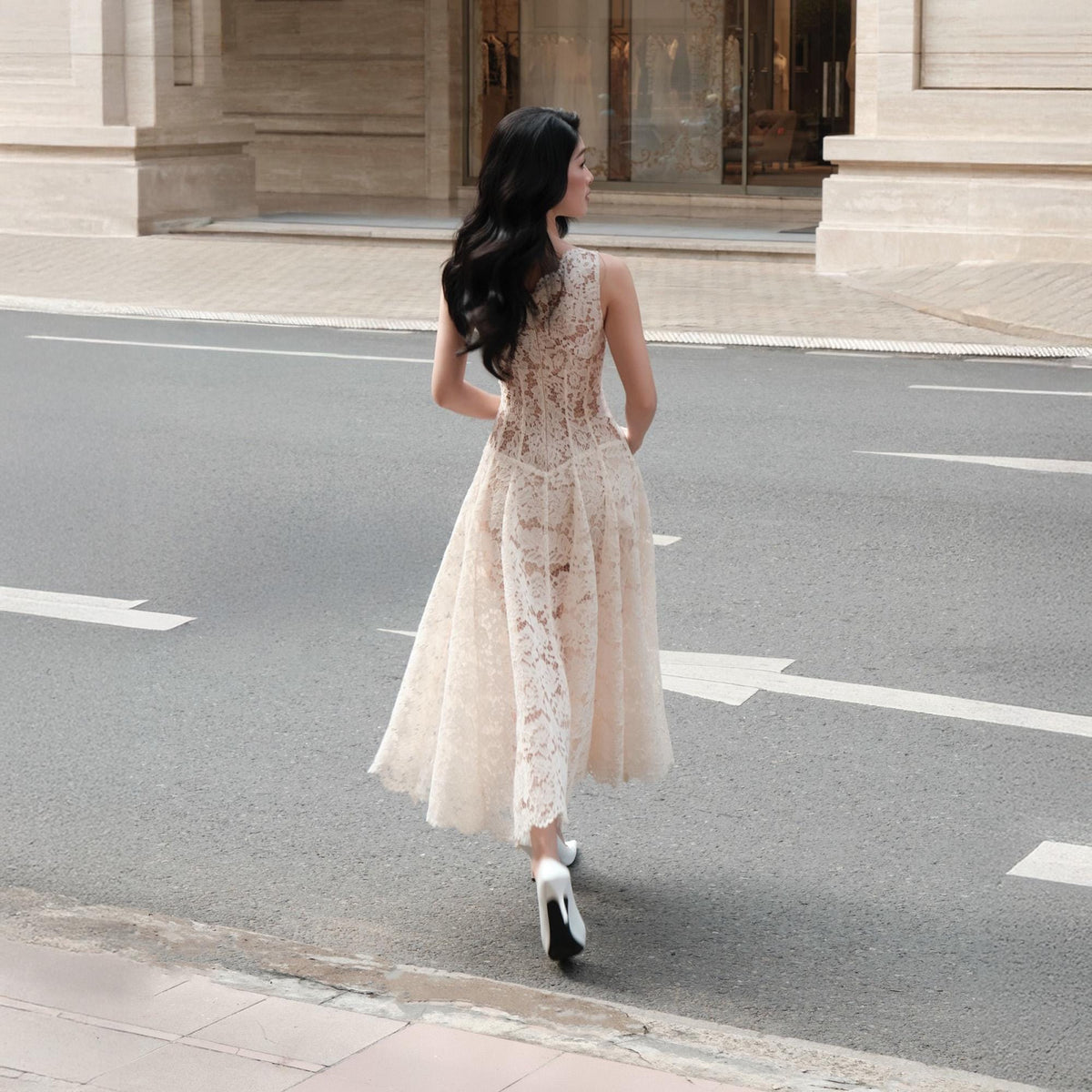 May include: A sleeveless midi dress crafted from cream-colored floral lace featuring a fitted bodice and a flared skirt. The garment is paired with white high-heeled shoes. The dress has a round neckline and a sheer lace overlay throughout the design.