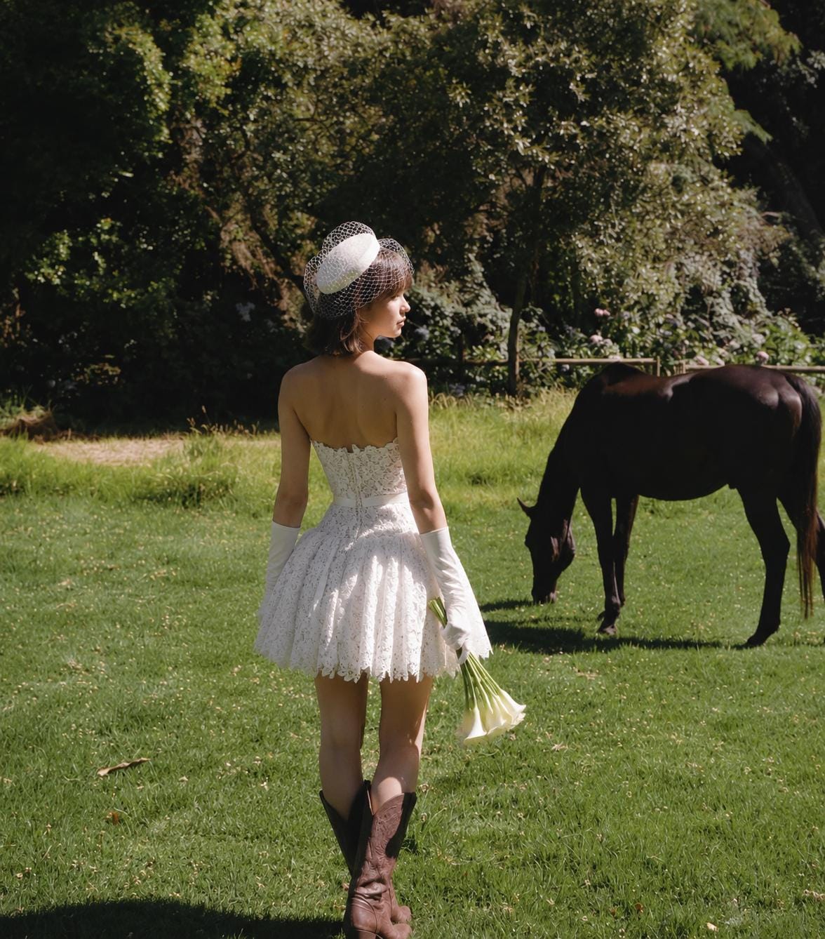 May include: A white strapless lace mini dress with a fitted bodice and a flared skirt, paired with a white pillbox hat featuring a delicate birdcage veil, long white opera gloves, and brown leather cowboy boots, while holding a bouquet of white lilies.