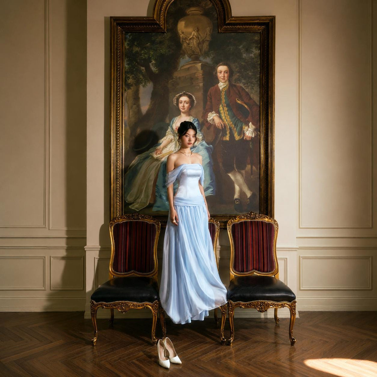 May include: A floor-length light blue gown featuring an off-the-shoulder neckline with draped sleeves, a fitted bodice, and a flowing skirt. The garment is positioned in front of a large framed oil painting depicting two figures in period attire.