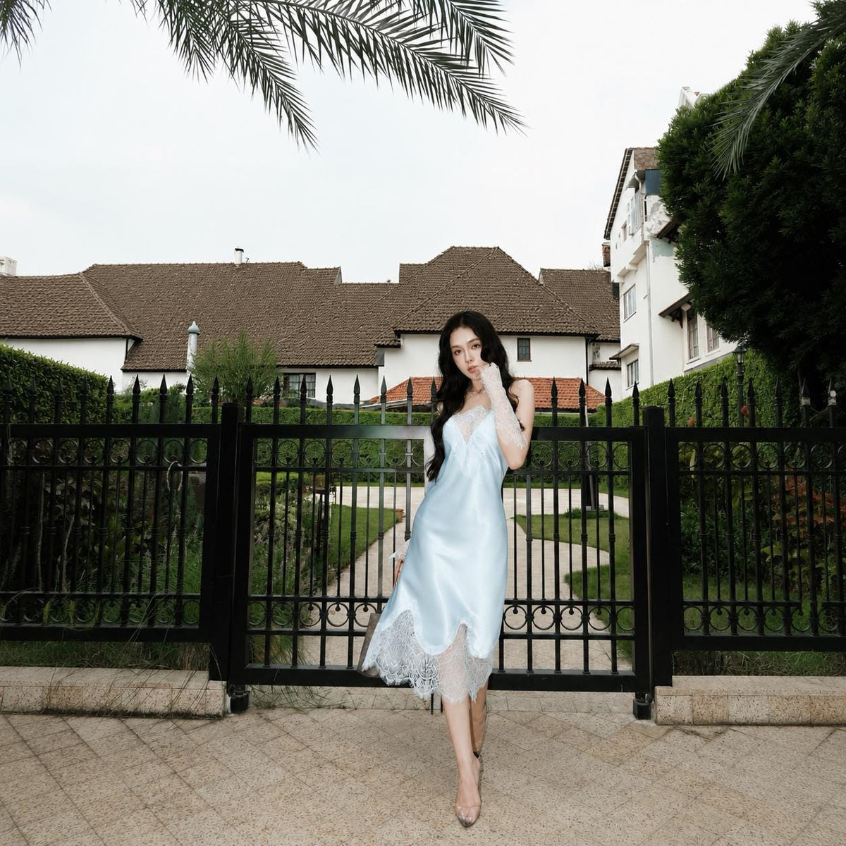 May include: A light blue satin slip dress featuring a V-neckline with white lace trim at the bodice and a wide, scalloped white lace hemline that falls below the knee. The garment has thin shoulder straps and a smooth, reflective fabric finish.