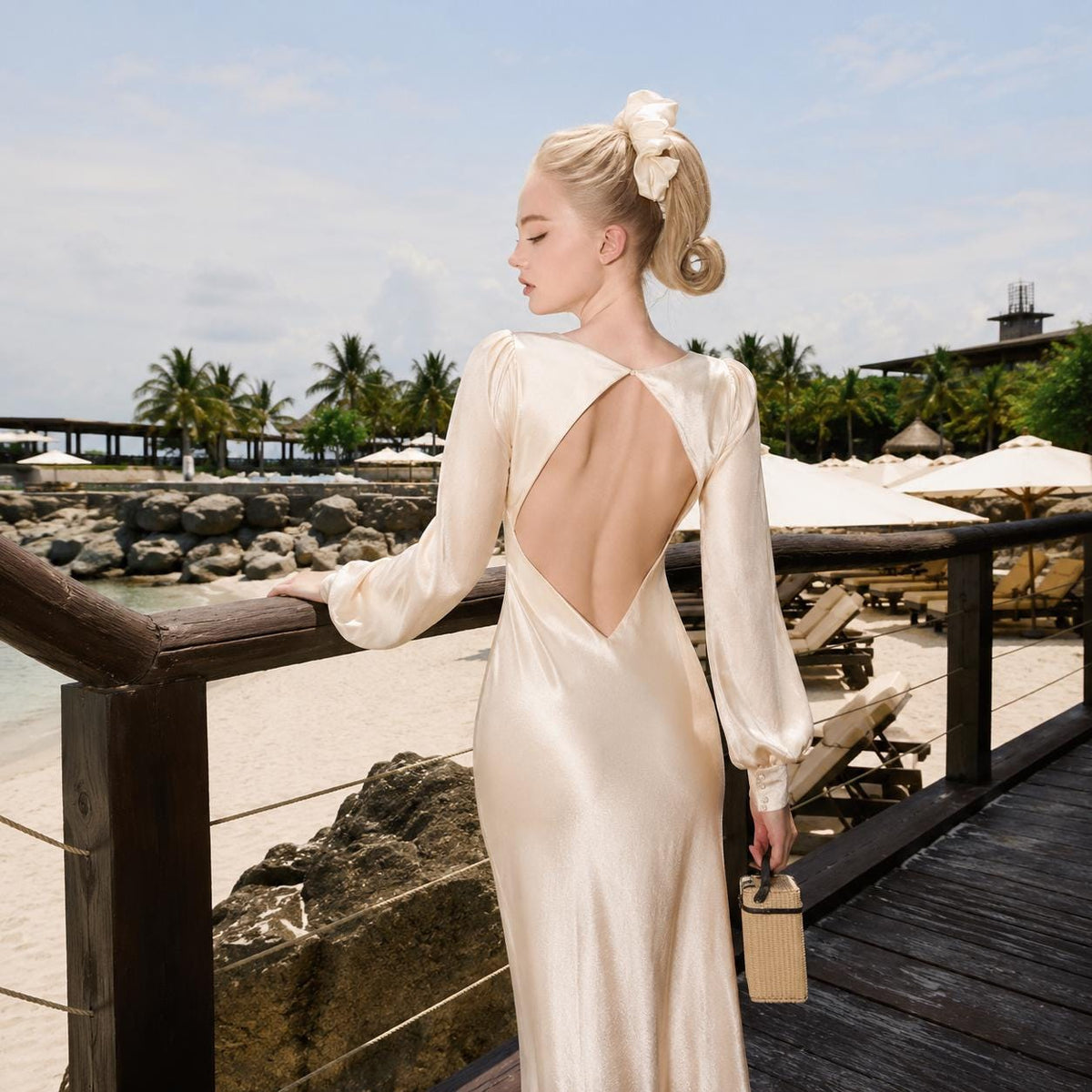 May include: A floor-length, champagne-colored satin dress featuring long, billowed sleeves and a deep, open-back design. The garment has a smooth, lustrous finish and a fitted silhouette that flows down to the hem, showcasing a refined, elegant aesthetic.