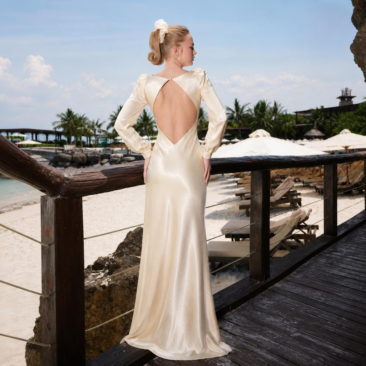 May include: A floor-length, long-sleeved champagne-colored satin dress featuring a deep open back design with a single button closure at the nape of the neck. The garment has a smooth, lustrous finish and a flowing, bias-cut skirt silhouette.
