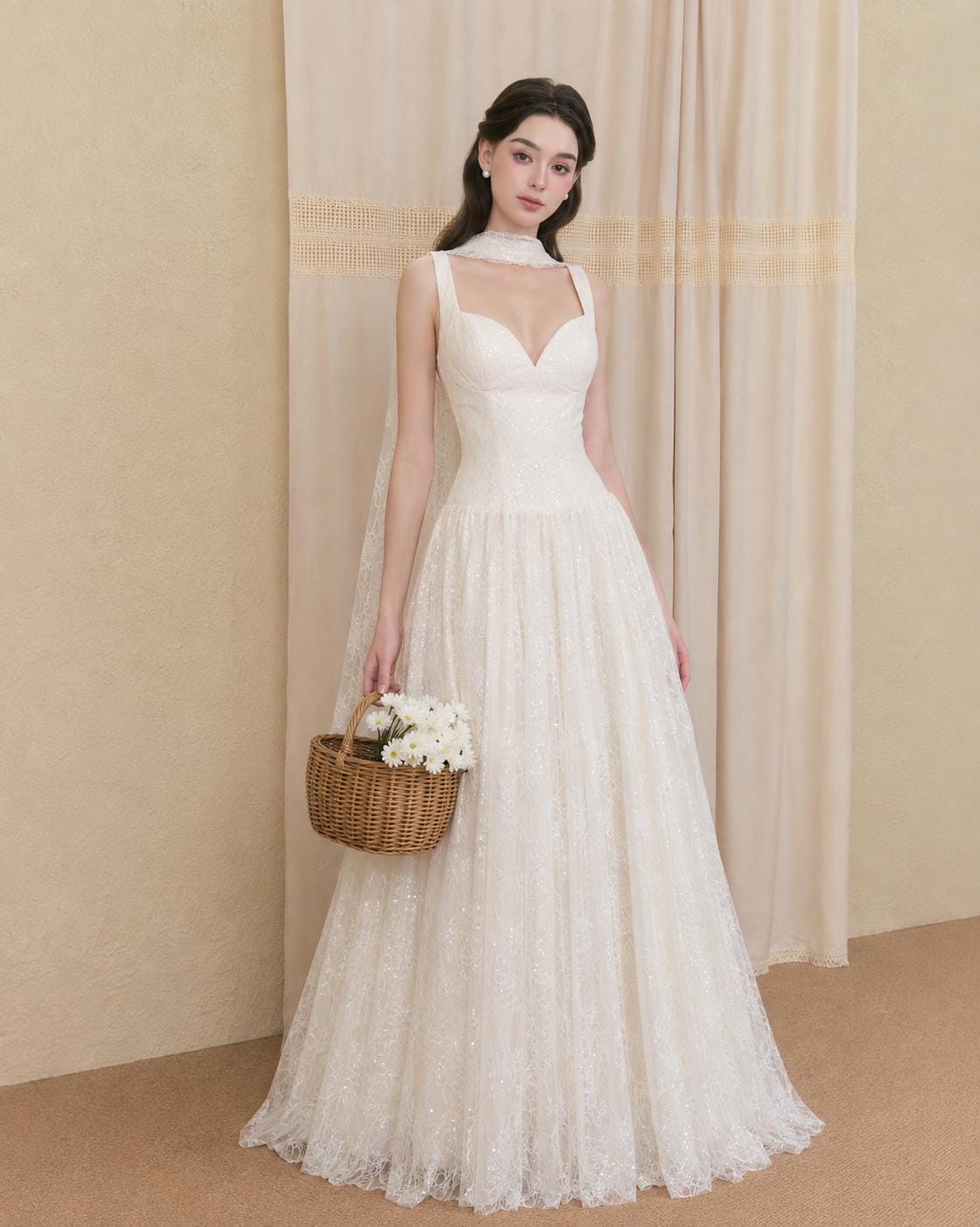May include: A floor-length white wedding dress featuring a sweetheart neckline, thick straps, and a full skirt with intricate lace detailing. The dress includes a matching sheer lace scarf draped around the neck and a small brown woven basket.