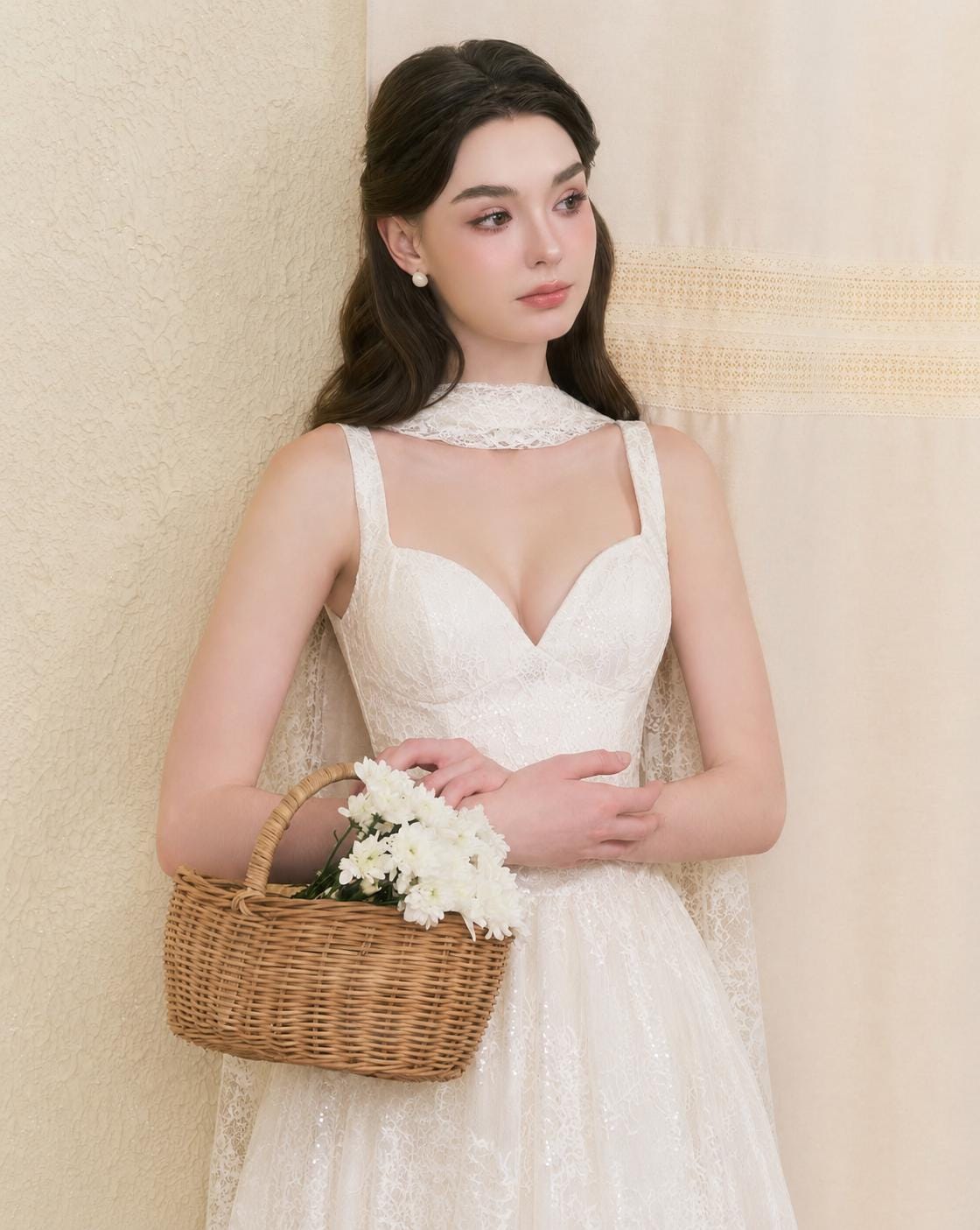 May include: A white lace dress featuring a sweetheart neckline, thick straps, and a matching lace neck scarf. The dress has a fitted bodice and a full skirt with intricate floral lace patterns. A small brown woven wicker basket holds white flowers.
